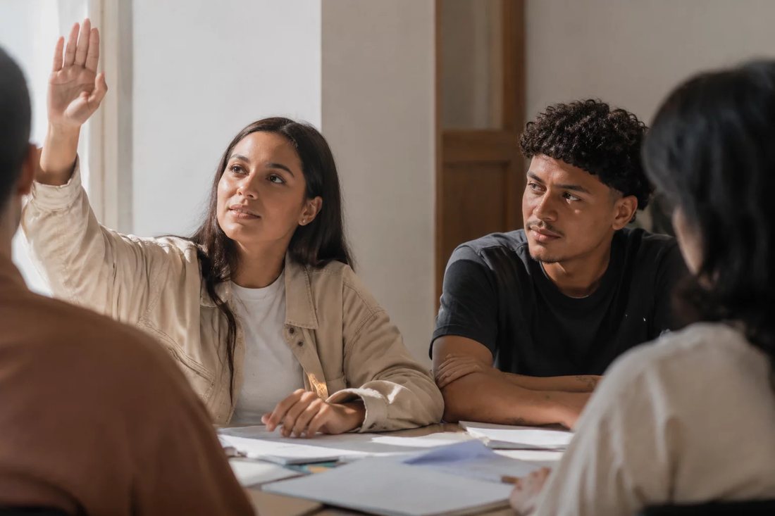 Facilitador de pé apontando para um argumento escrito no quadro durante a sessão